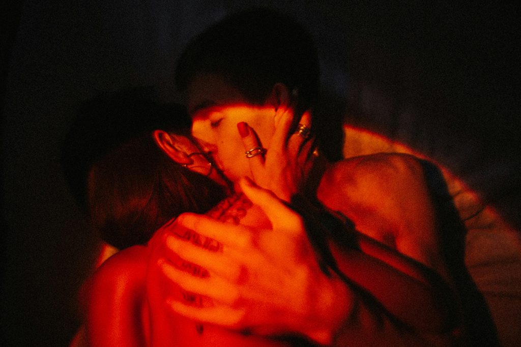 couple embracing in bed under a red light
