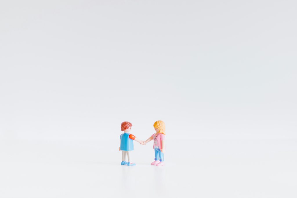 two plastic small figurines posed as if they're shaking hands